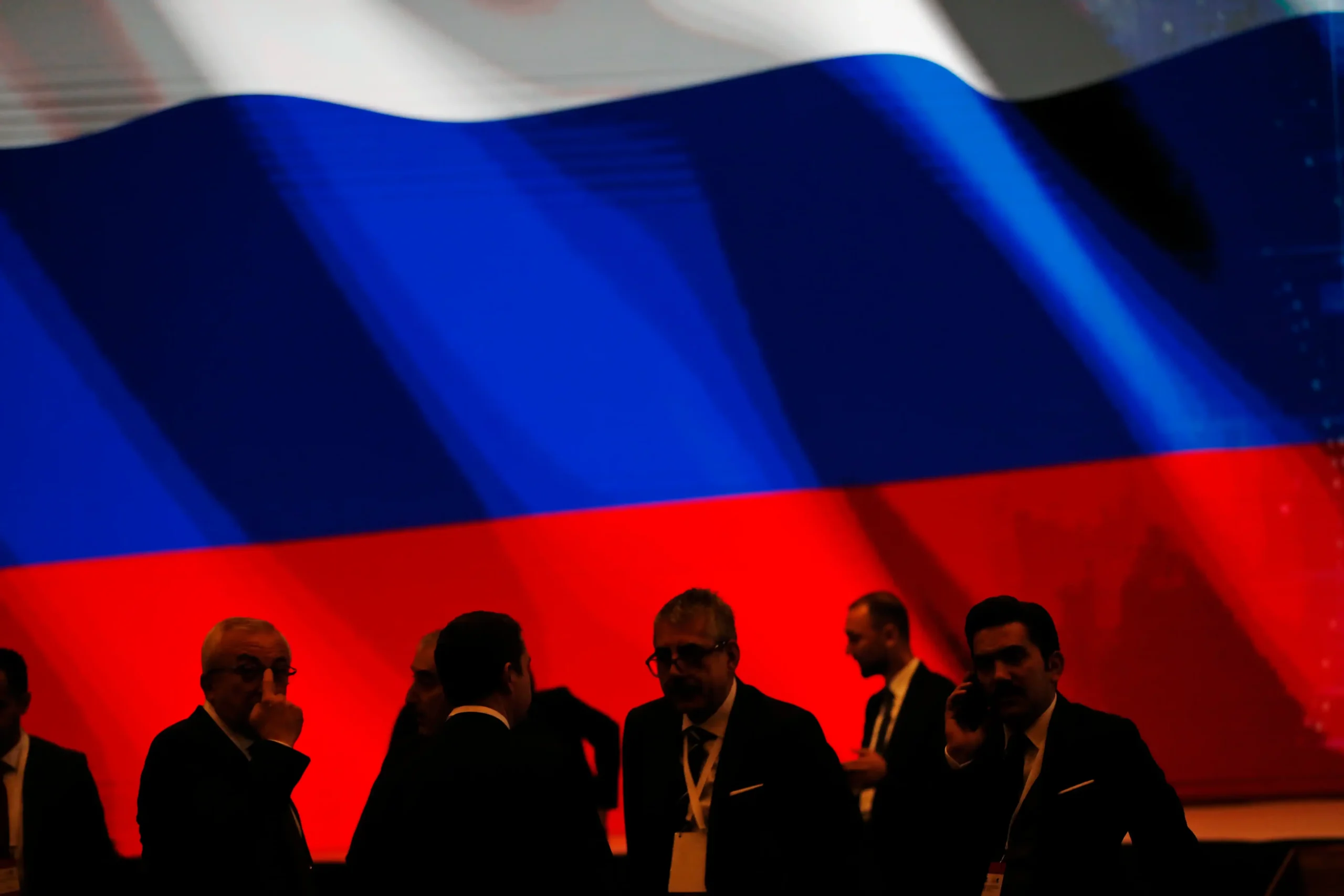 Backdropped by Russia s flag officials wait