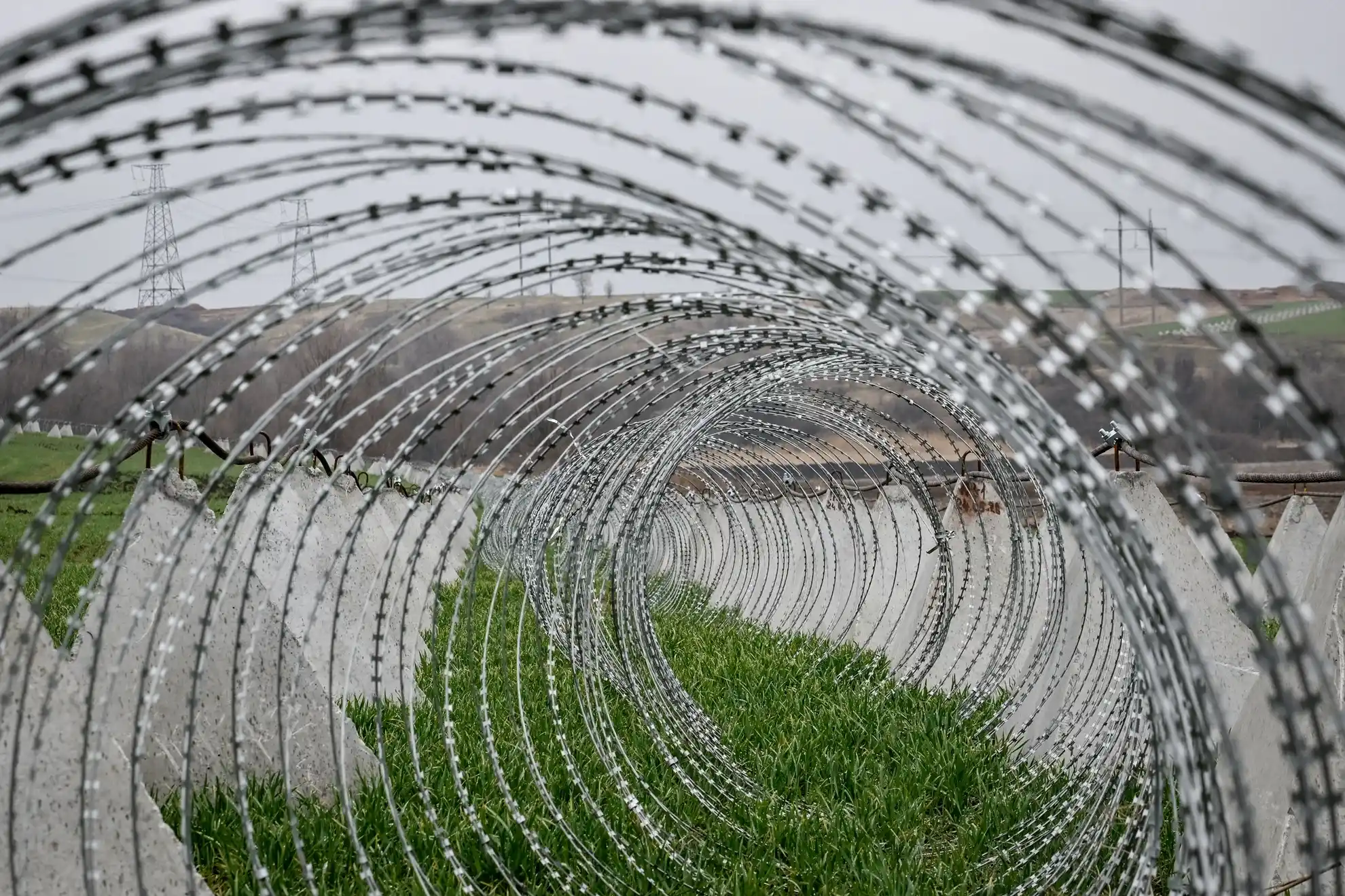 Колючая проволока в форме спирали и противотанковые сваи