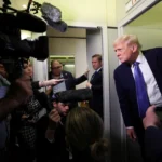 U.S. President Donald Trump speaks to reporters aboard Air Force One