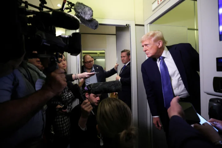 U.S. President Donald Trump speaks to reporters aboard Air Force One