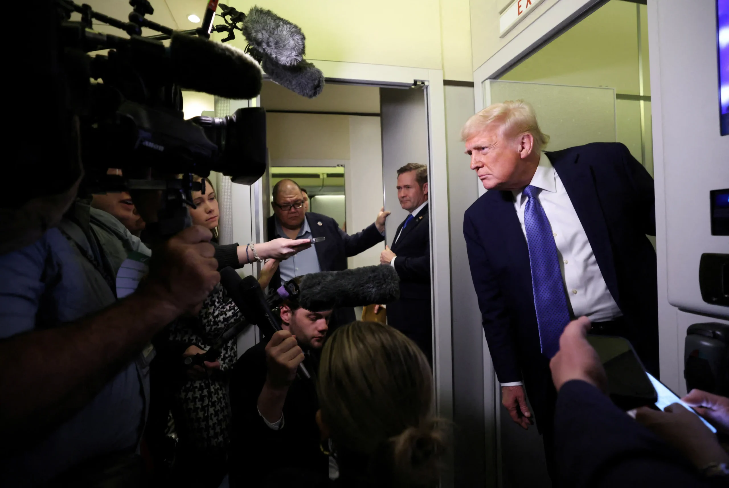 U.S. President Donald Trump speaks to reporters aboard Air Force One