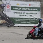 Люди едут на мопеде мимо баннера