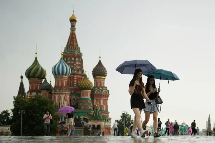 People walk across Red Square with umbrellas