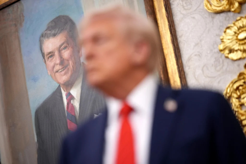 Дональд Трамп стоит под портретом Рональда Рейгана