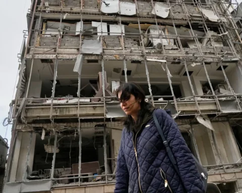 Женщина проходит мимо поврежденной больницы