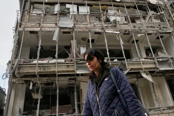 Женщина проходит мимо поврежденной больницы